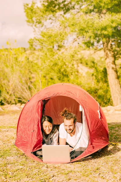 Giovani pantaloni a vita bassa che si rilassano in tenda con il computer portatile