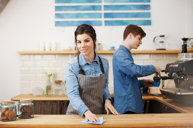 Giovani simpatici baristi in uniforme che lavorano al bancone del bar.