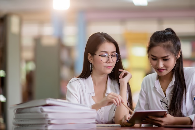 Giovani studenti che imparano, scaffali di biblioteca