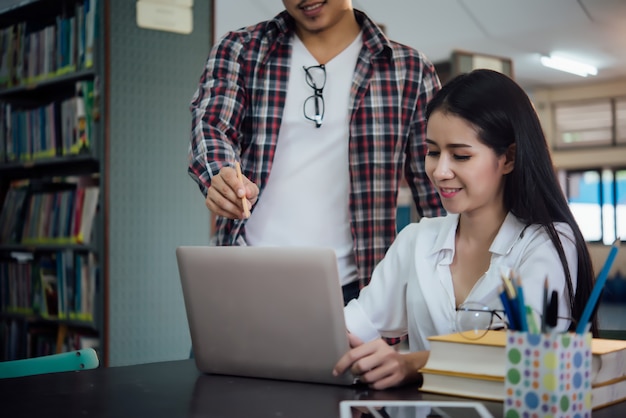 Giovani studenti che imparano, scaffali di biblioteca