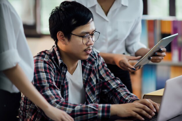 Giovani studenti che imparano, scaffali di biblioteca