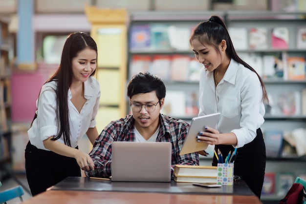 Giovani studenti che imparano, scaffali di biblioteca