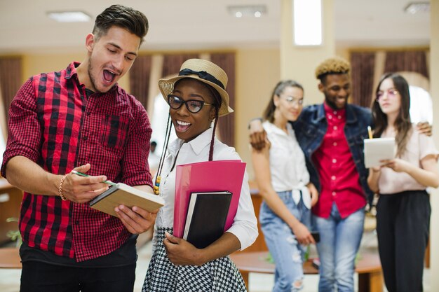 Giovani studenti di successo che presentano con il taccuino