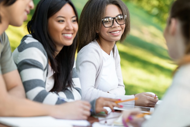 Giovani studenti seduti e che studiano all'aperto mentre parlano