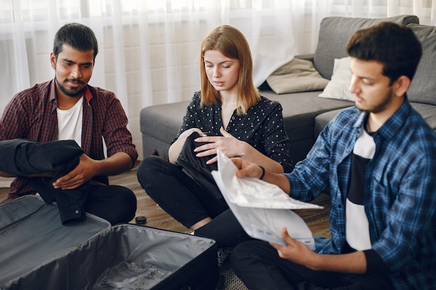 Giovani uomini e donne che si preparano per un viaggio. Viaggiatori che imballano vestiti e bagagli in una valigia.