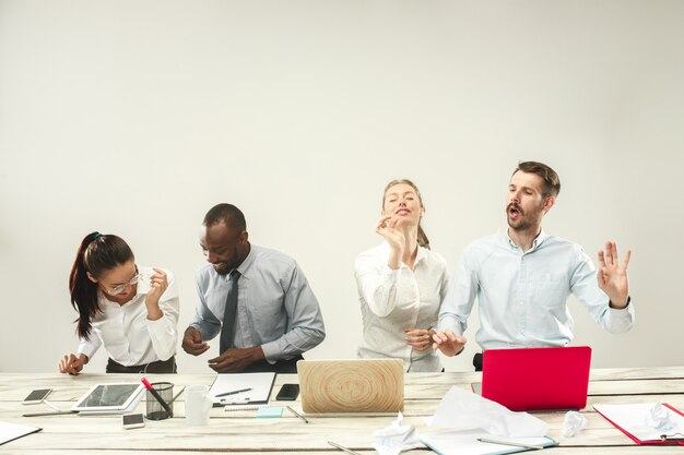 Giovani uomini e donne seduti in ufficio e lavorando su laptop. Concetto di emozioni