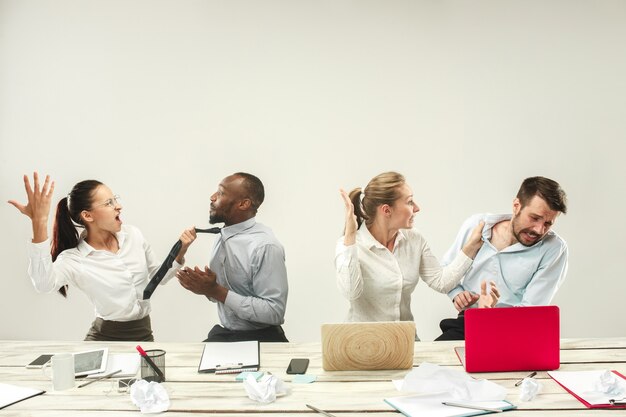 Giovani uomini e donne seduti in ufficio e lavorando su laptop. Concetto di emozioni