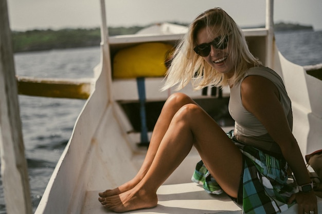 Gita in barca a Bali. Una giovane donna con gli occhiali da sole sta navigando su una barca verso un'isola vicina.