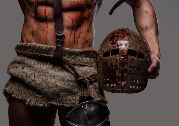 Gladiatore con corpo muscoloso che tiene un elmo