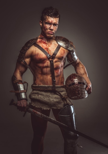 Gladiatore sanguinante muscoloso con spada ed elmo.