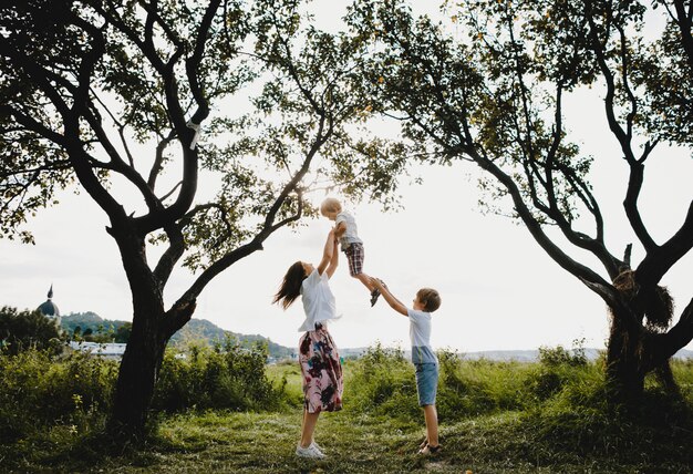 Gli abbracci affascinanti della giovane madre tengono i suoi piccoli figli che stanno sotto