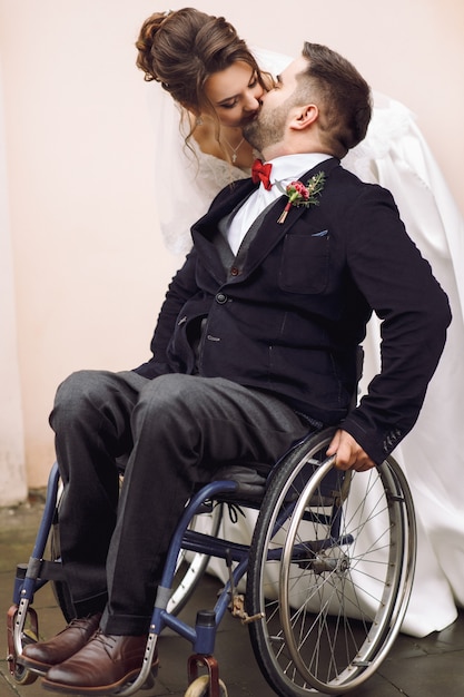 Gli abbracci della sposa governano sulla sedia a rotelle da dietro la posa sulla via