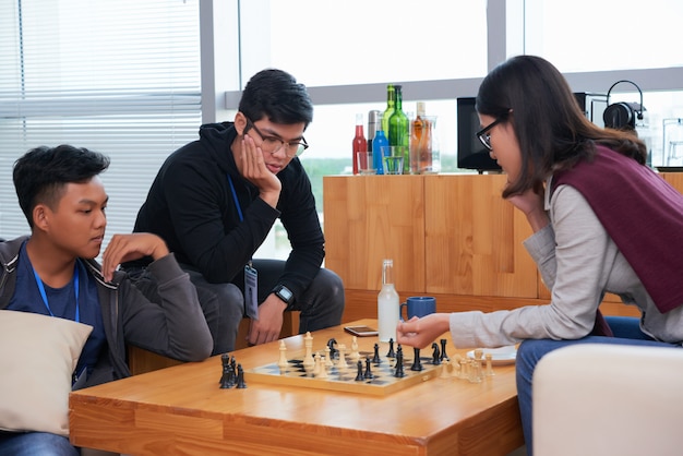 Gli adolescenti asiatici giocano a scacchi con il loro amico a guardare la partita