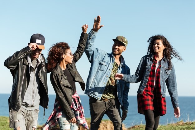 Gli amici africani sorridenti che camminano si danno il cinque l'un l'altro.