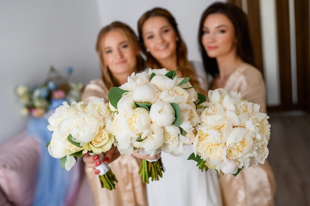 Gli amici e la sposa della sposa che tengono i mazzi bianchi