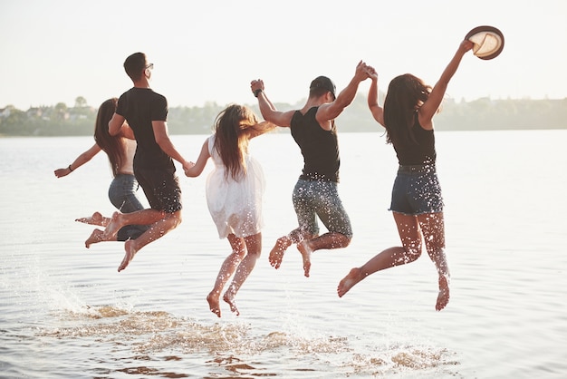 Gli amici felici si divertono sulla spiaggia - Giovani che giocano in acqua all'aperto durante le vacanze estive.