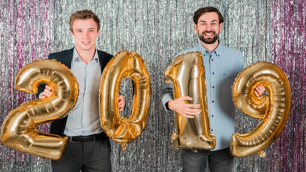 Gli amici in posa con palloncini dorati a una festa di Capodanno