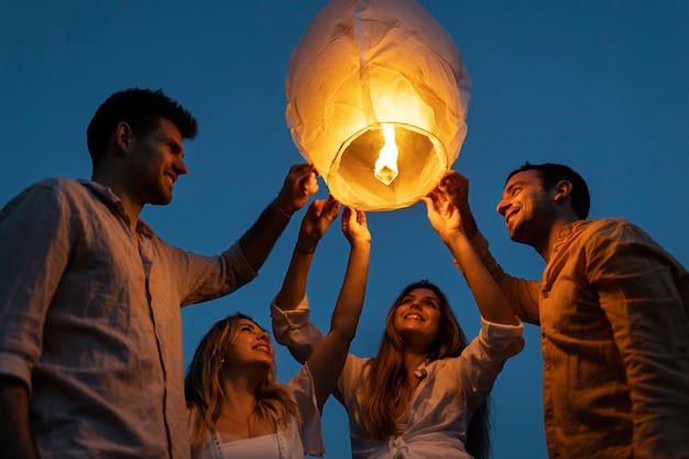 Gli amici in spiaggia lanciano lanterna durante la notte