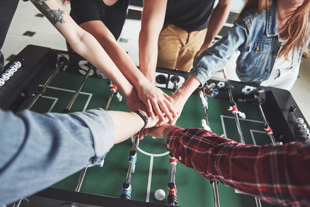 Gli amici insieme giocano a giochi da tavolo, calcio balilla, si divertono nel tempo libero.