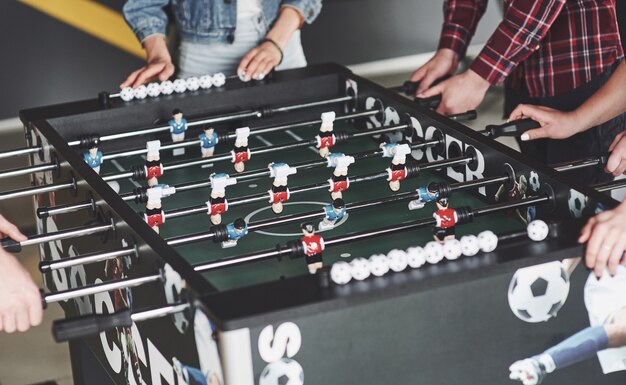 Gli amici insieme giocano a giochi da tavolo, calcio balilla