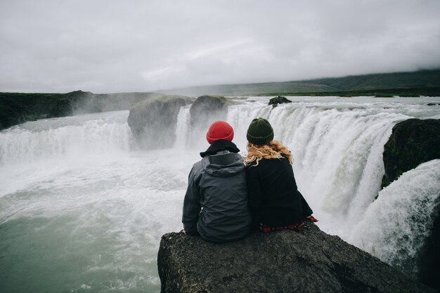 Gli escursionisti di coppia si siedono sulla scogliera della cascata