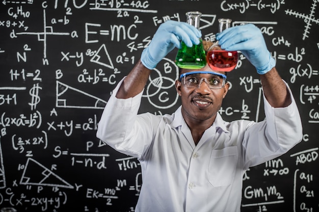 Gli scienziati osservano le sostanze chimiche verdi e rosse in vetro presso il laboratorio