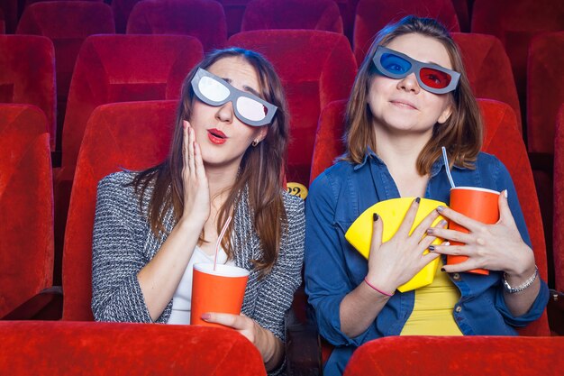 Gli spettatori seduti al cinema e guardare film con tazze di popcorn.