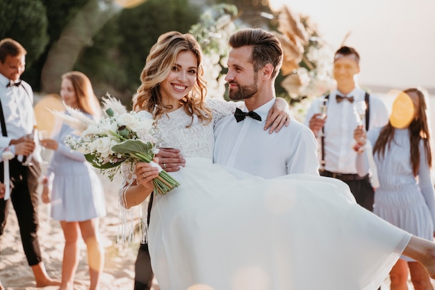 Gli sposi festeggiano il loro matrimonio con gli ospiti sulla spiaggia