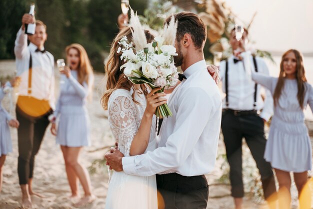 Gli sposi festeggiano il loro matrimonio con gli ospiti sulla spiaggia