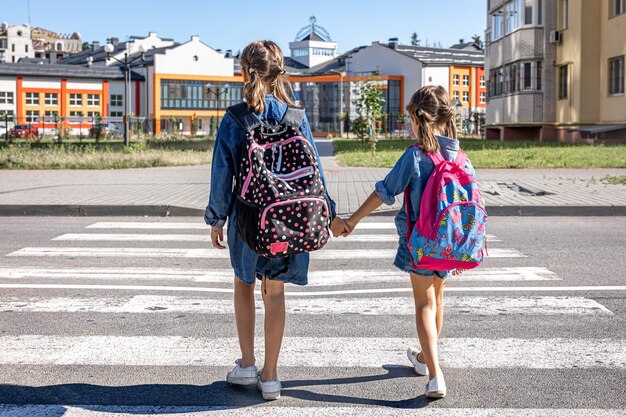 Gli studenti della scuola primaria vanno a scuola, tenendosi per mano, il primo giorno di scuola, il ritorno a scuola.