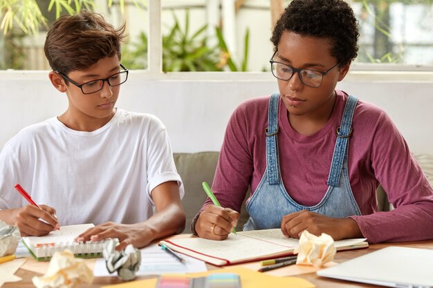 Gli studenti universitari si sono concentrati sulla scrittura, siedono al desktop, prendono appunti sul taccuino