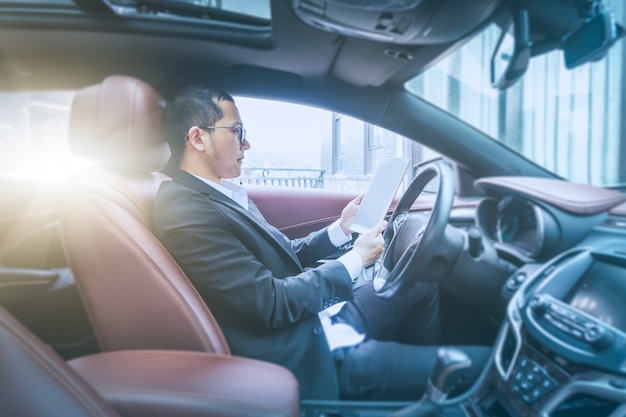 Gli uomini d&#39;affari lavorano con i computer tablet nelle loro auto