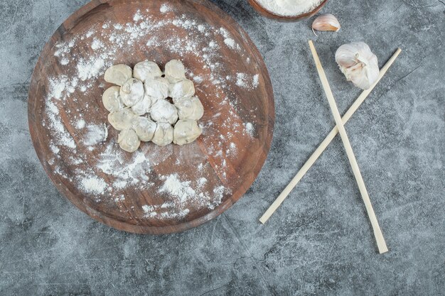 Gnocchi crudi sul piatto di legno con le bacchette.