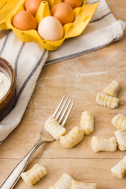 Gnocchi di patate fatti in casa freschi crudi con forcella sul tavolo di legno