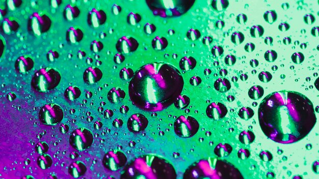 Gocce d&#39;acqua fresca sullo sfondo riflettente verde e viola