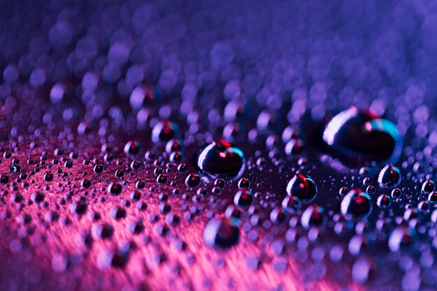 Gocce d&#39;acqua su una superficie di vetro brillante blu e rosa