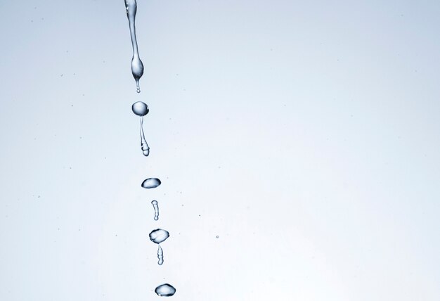Gocce di liquido trasparente su sfondo chiaro con spazio di copia