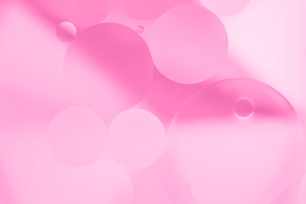 Gocce di olio rosa sulla superficie dell&#39;acqua