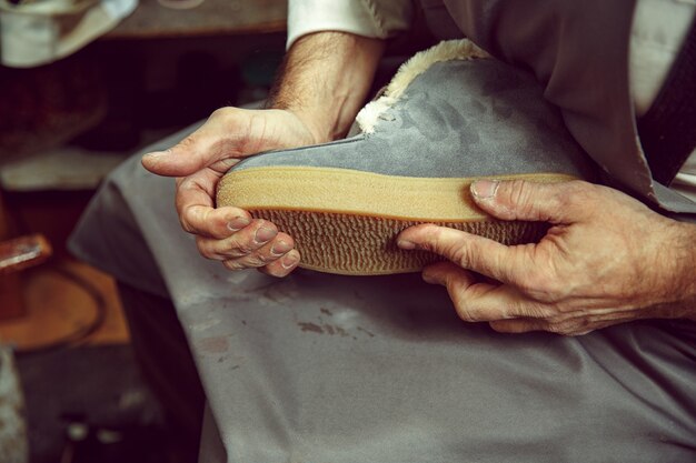 Godendo del processo di creazione di scarpe su misura. Luogo di lavoro del designer di scarpe. Mani del calzolaio che si occupa di strumento calzolaio, primi piani