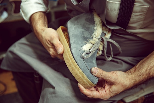 Godendo del processo di creazione di scarpe su misura. Luogo di lavoro del designer di scarpe. Mani del calzolaio che si occupa di strumento calzolaio, primi piani