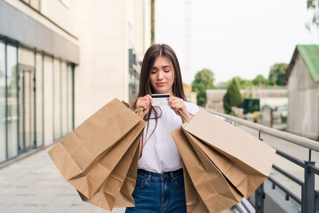 Godersi lo shopping di un giorno. Integrale della giovane donna che tiene i sacchetti della spesa e sorride mentre cammina lungo la strada