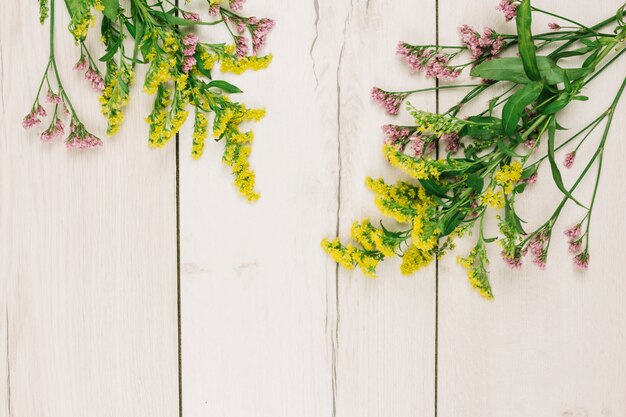 Goldenrods rosa e giallo o solidago gigantea fiorisce sopra la scrivania in legno