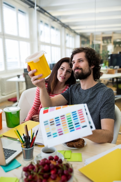 grafici maschili e femminili in possesso di un contenitore di plastica e carta colori