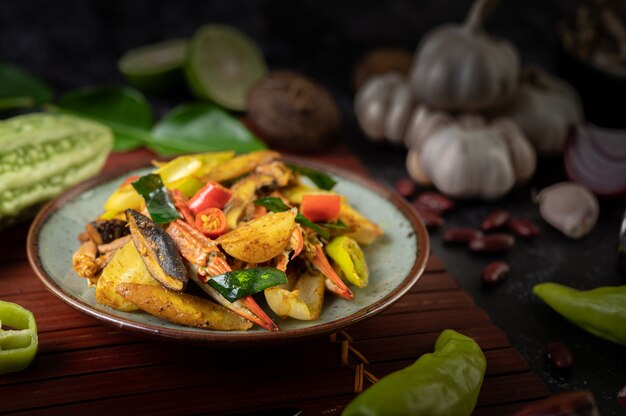 Granchio fritto con curry in polvere in un piatto con peperoni e pomodori.