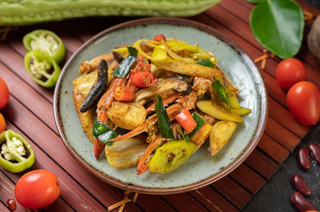 Granchio fritto con curry in polvere in un piatto con peperoni e pomodori.