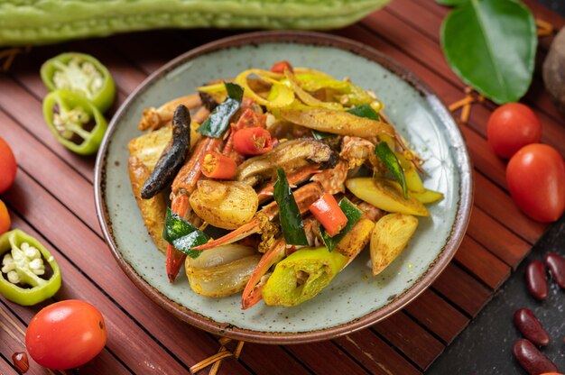 Granchio fritto con curry in polvere in un piatto con peperoni e pomodori.