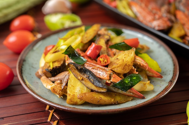 Granchio fritto con curry in polvere in un piatto con peperoni e pomodori.