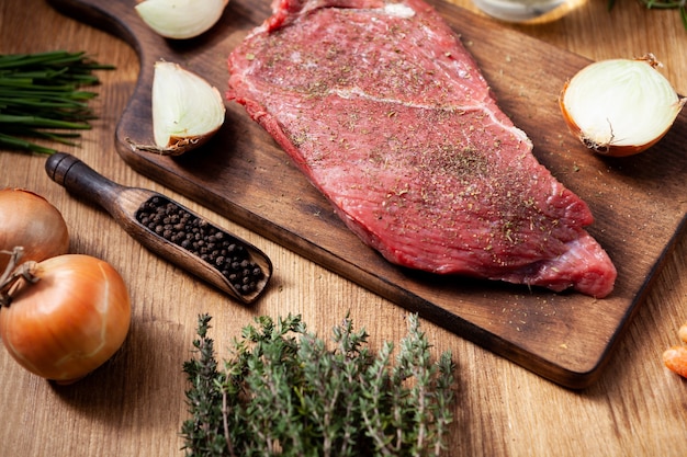 Grande carne cruda saporita sul tagliere con rosmarino. Pepe nero. stagionatura