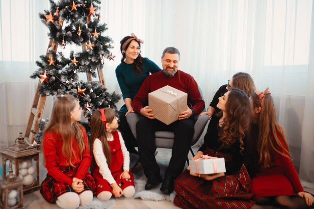 Grande famiglia che si siede a casa vicino all'albero di Natale