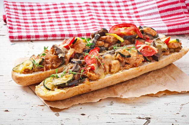 Grande panino con verdure arrosto (zucchine, melanzane, pomodori) con formaggio e timo su fondo in legno vecchio